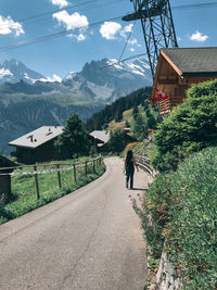 Rear view of woman walking on road amidst buildings