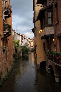 Canal amidst buildings in city against sky