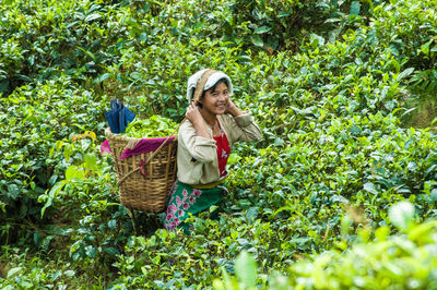 Portrait of a smiling young woman standing against plants