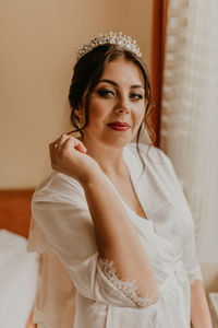 Portrait of young woman sitting on bed at home