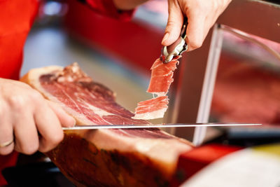 Cropped hands of chef cutting meat in kitchen