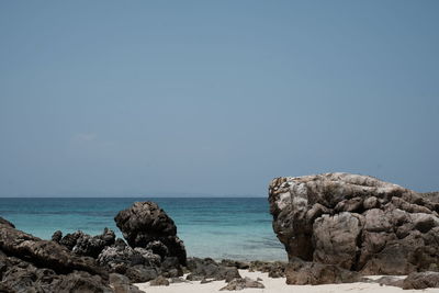 Rocks on beach against clear sky