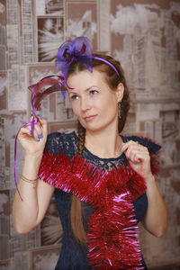 Portrait of smiling young woman standing against wall