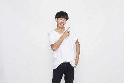 Portrait of young man standing against white background