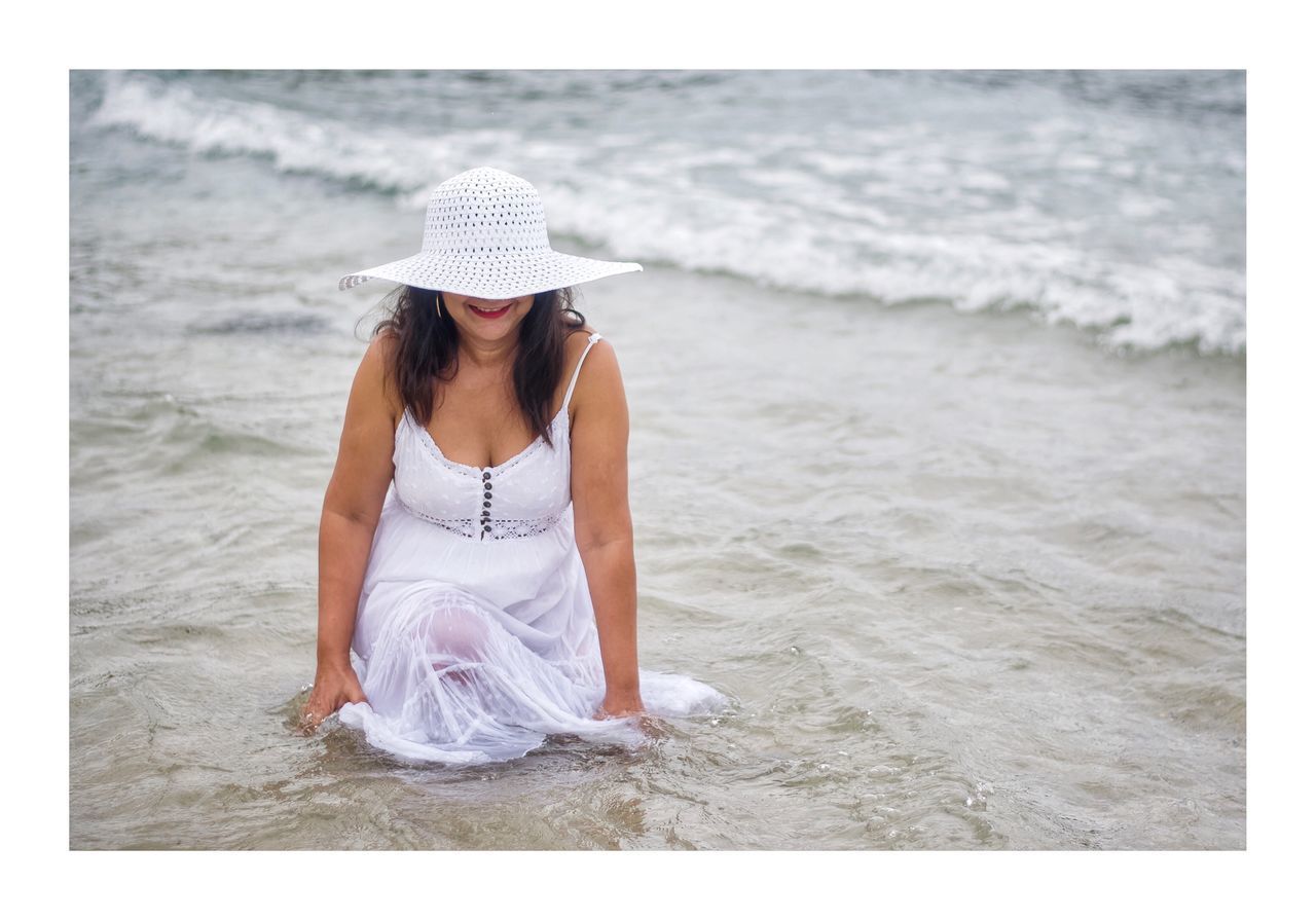 YOUNG WOMAN SITTING ON BEACH