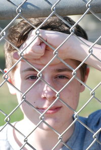 Portrait of young woman seen through chainlink fence