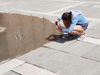 High angle view of woman sitting on footpath