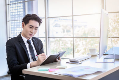 Young man using mobile phone while sitting on table