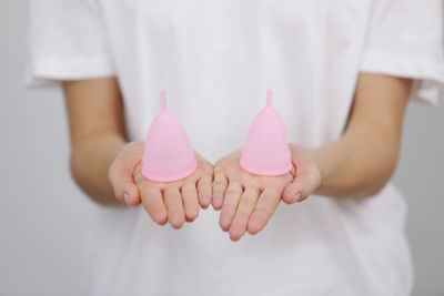 Midsection of woman holding heart shape against white background