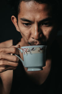 Close-up portrait of woman holding coffee cup