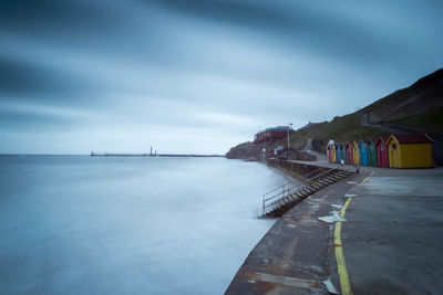 Pier on sea against cloudy sky