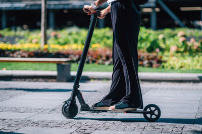 Low section of woman riding electric scooter on footpath