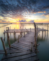 Pier over sea against sky during sunset