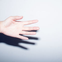 Close-up of hand touching shadow over white background