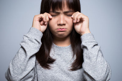 Sad young woman against gray background