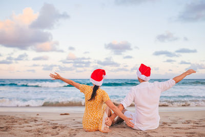 Rear view of woman standing at beach against sky