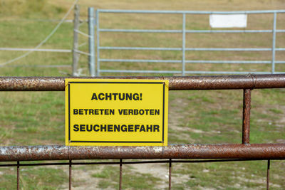 Yellow sign on a metal fence with the words warning - do not enter - danger of epidemics 