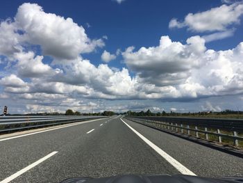 Road passing through landscape against cloudy sky