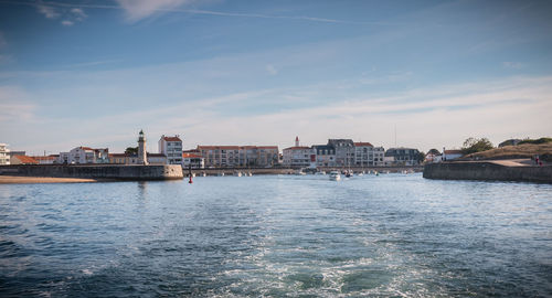 Sea by buildings against sky in city