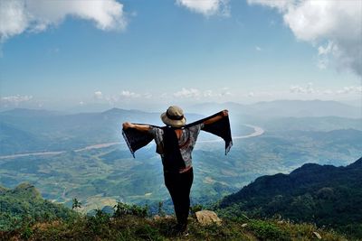 Rear view of woman with arms outstretched standing on mountain