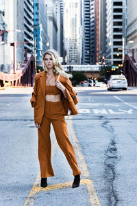 Portrait of young woman standing on road in city