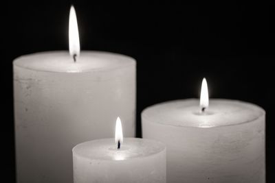 Close-up of lit candles against black background