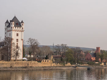 Buildings by river against clear sky