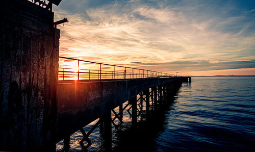 Bridge over sea against sky during sunset