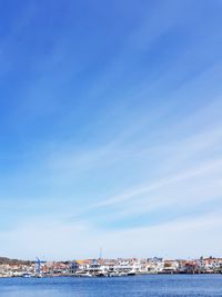 View of harbor by sea against blue sky