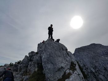 Low angle view of man standing on rock against sky