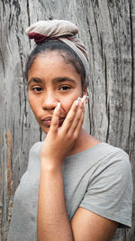 Portrait of young woman sitting against a dry tree