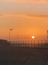 Street lights by road against orange sky