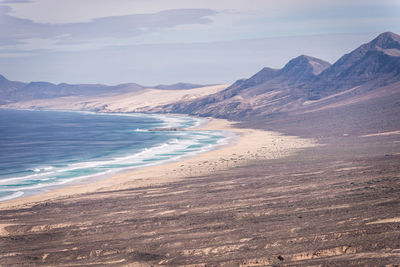 Scenic view of beach and mountains against sky