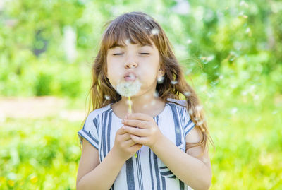 Cute girl blowing dandelion seed