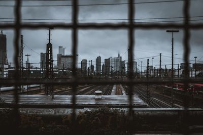 Railroad tracks by buildings in city against sky