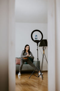 Full length of woman sitting on hardwood floor