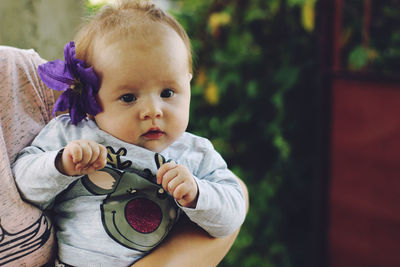 Midsection of mother holding cute daughter wearing purple flower