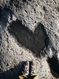 Low section of man standing by heart shape on rock