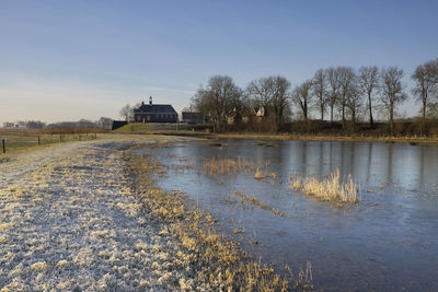 House by lake against sky