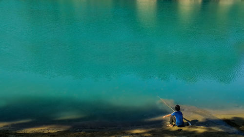 Boy sitting by lake