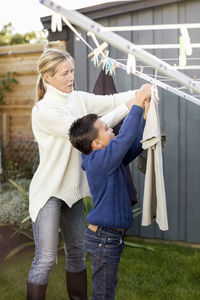 Mother and son drying laundry at yard