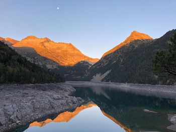 Scenic view of lake by mountains against clear sky