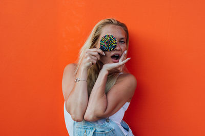 Portrait of woman holding brush against orange background