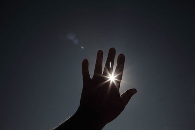 Close-up of silhouette hand against sky at night