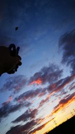 Cropped image of airplane flying against sky during sunset