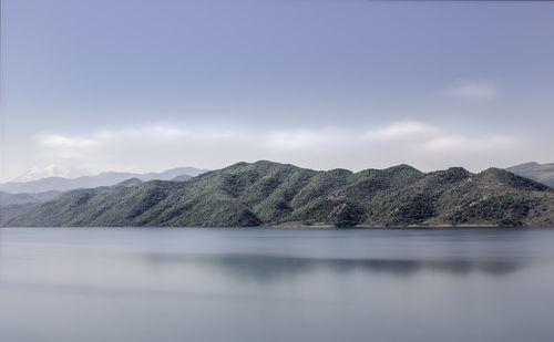 Scenic view of lake by mountains against sky