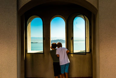 Rear view of man and woman looking through window