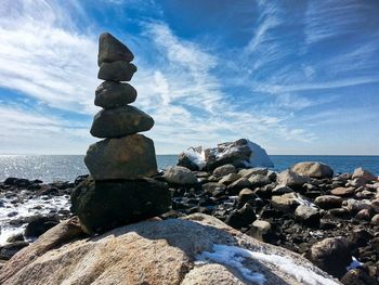 Stack of stones on rock against sky