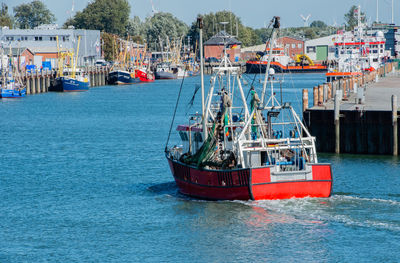 Fishing boats moored at harbor against sky