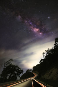 Road amidst trees against sky at night